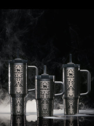Three Stanley mugs with decorative patterns on a dark background