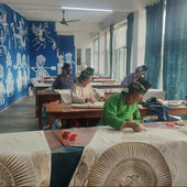 Classroom with students in green uniforms working on crafts, surrounded by blue and green murals.