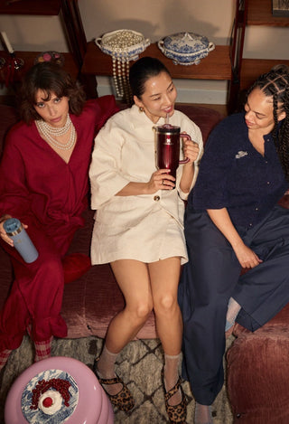 Three women sitting on a plush couch in a cozy room with decorative elements.