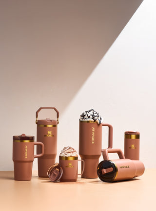 Set of brown insulated mugs with gold accents on a neutral background