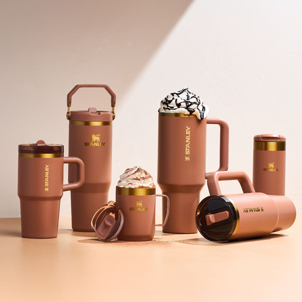 Collection of brown Stanley mugs on a beige background