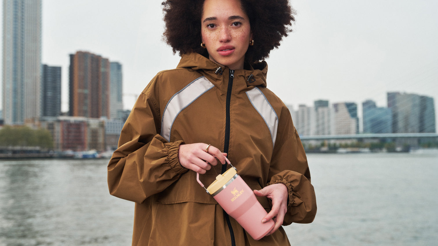 Woman holding a pink water bottle with a cityscape in the background