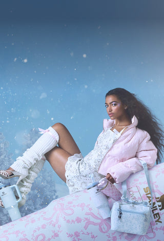 Woman in a pink outfit sitting on a bench with a snowy background
