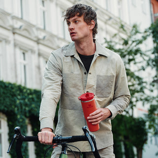 Front shot camera of a model on a bike holding the IceFlow FlipStraw Tumbler