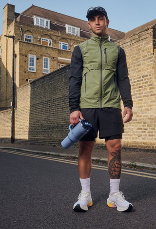 Man in athletic wear standing on a street with buildings in the background